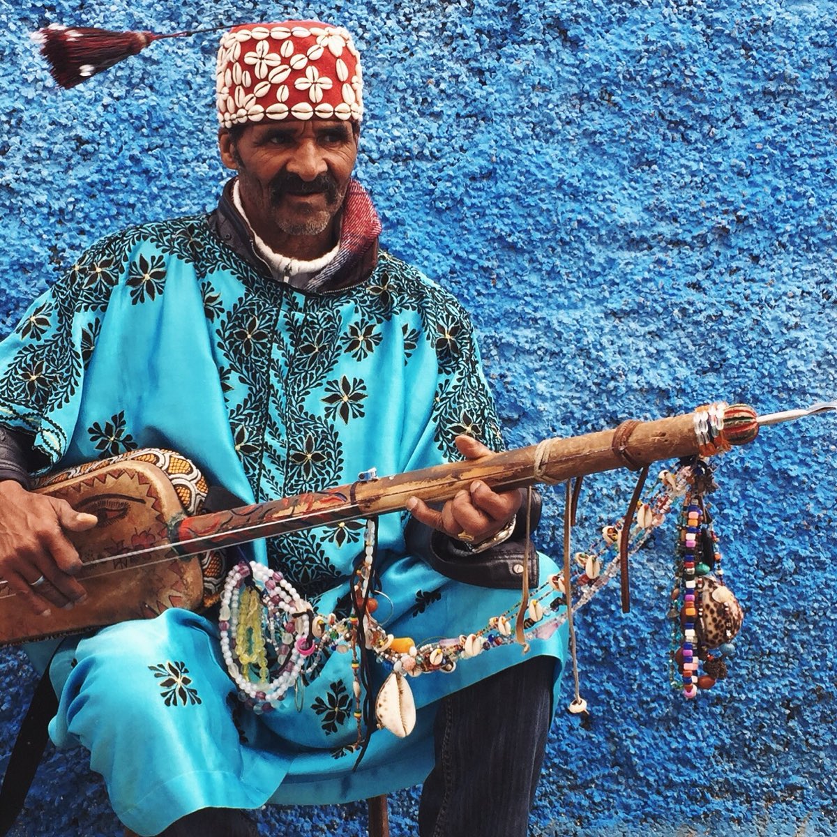 Gnawa musician in blue robe playing a guembri